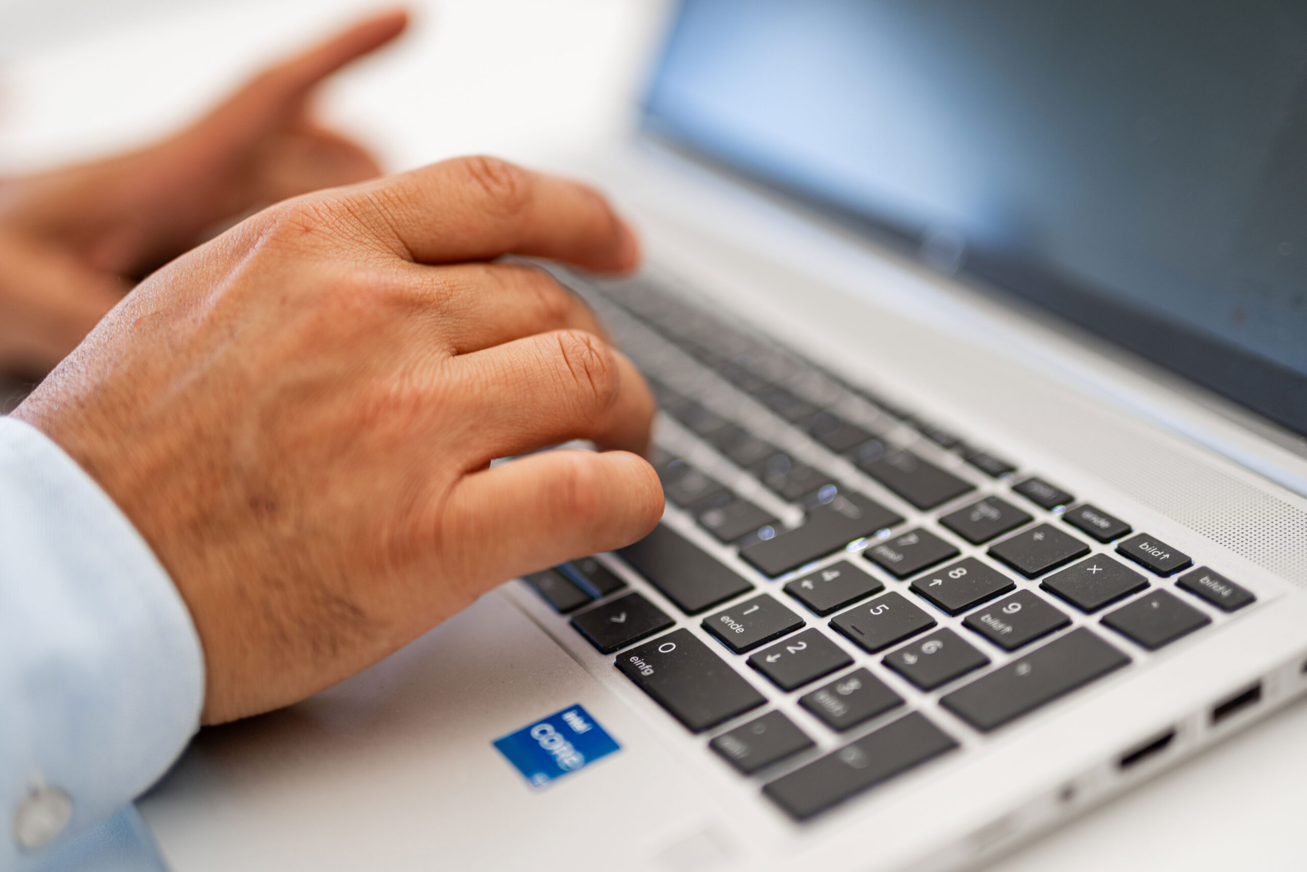 Hände einer Person bei der Arbeit an einem Laptop zur Bearbeitung steuerrelevanter Daten im Bereich Abgeltungssteuer.