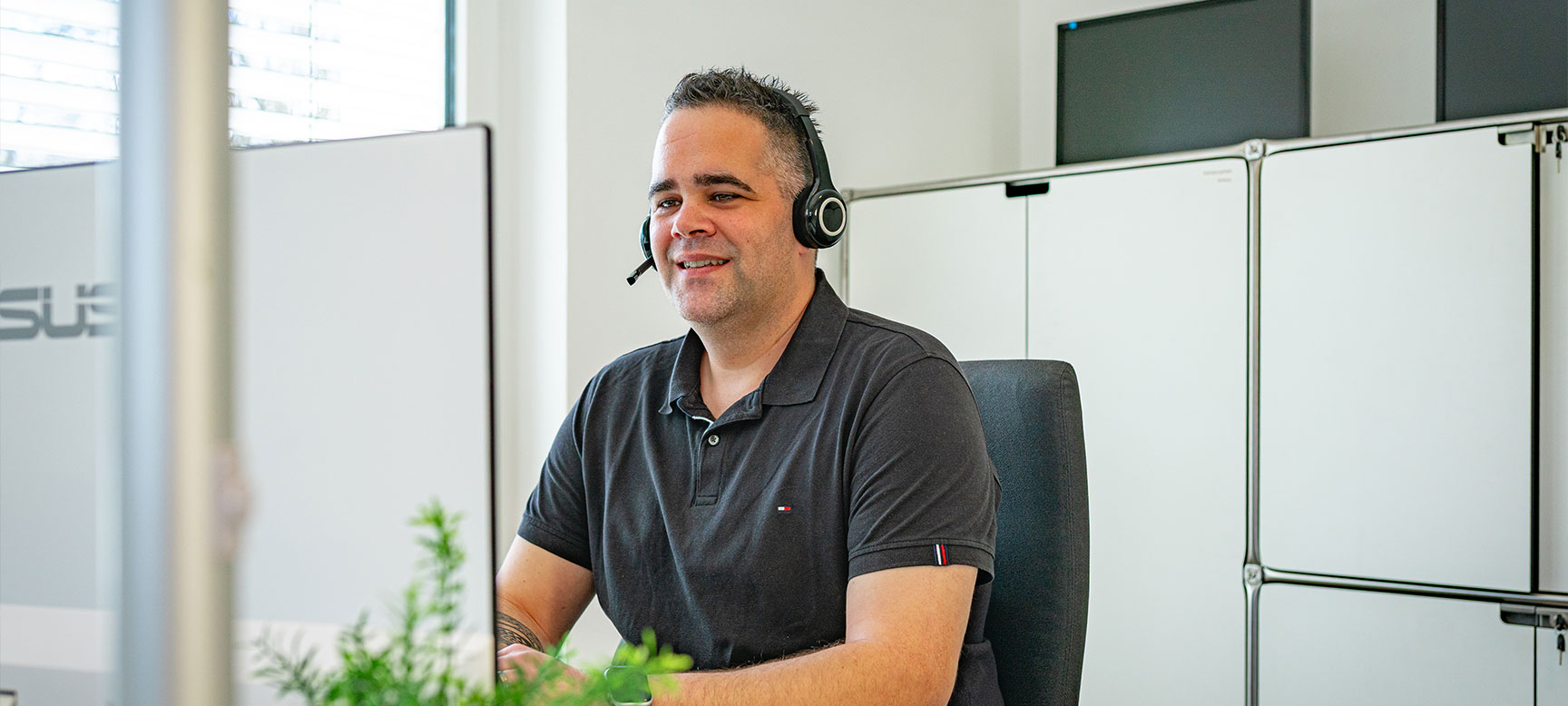 AlphaTax-Mitarbeiter mit Headset an einem Arbeitsplatz im Kundensupport.