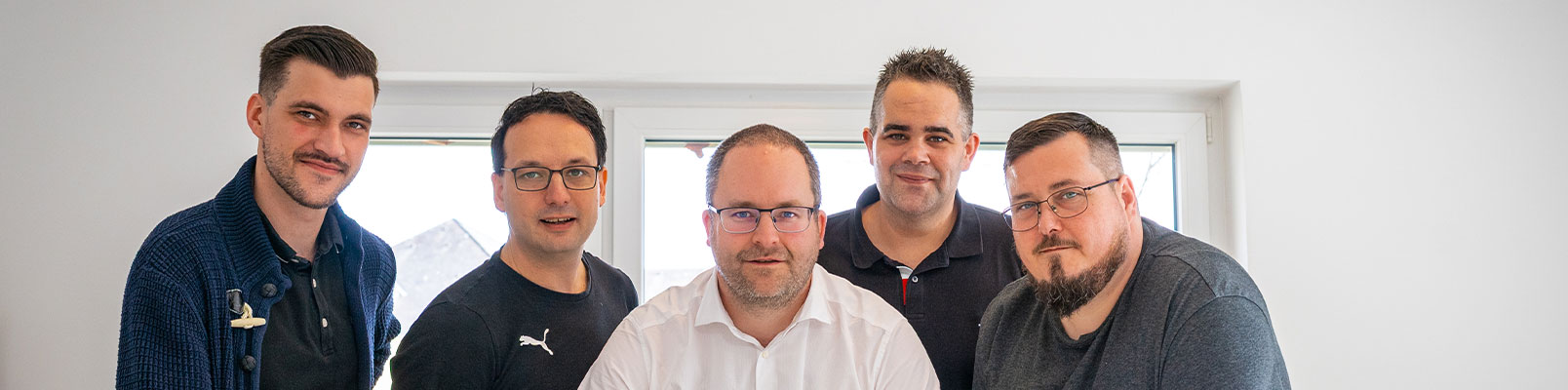 Fünf Mitarbeitende des AlphaTax-Teams in den Büroräumen des Unternehmens.